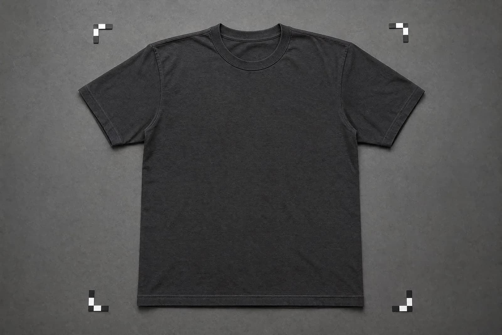 A charcoal t-shirt laid out flat and squared on a grey surface with corner markers at each corner, unworn.